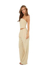 A woman modeling a light beige two-piece set consisting of a strapless crop top and matching wide-leg pants, photographed against a plain white studio background.